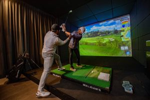 Jugador de golf concentrado durante una clase en Mulligan's, listo para comenzar el año con nuevos logros.